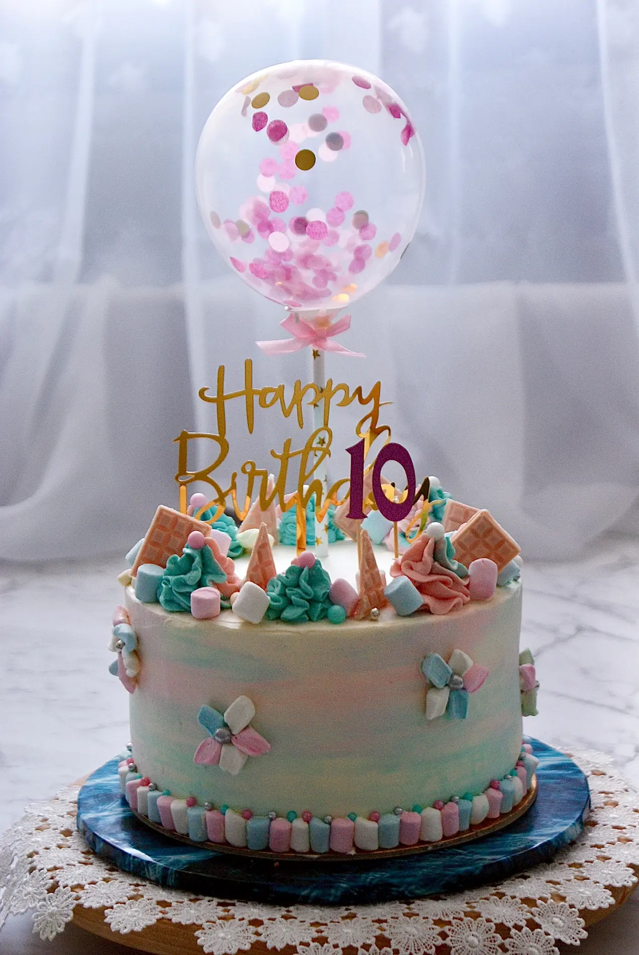 Tort dziecięcy na 10 urodziny w pastelowych kolorach z balonem konfetti, wafelkami i piankami
