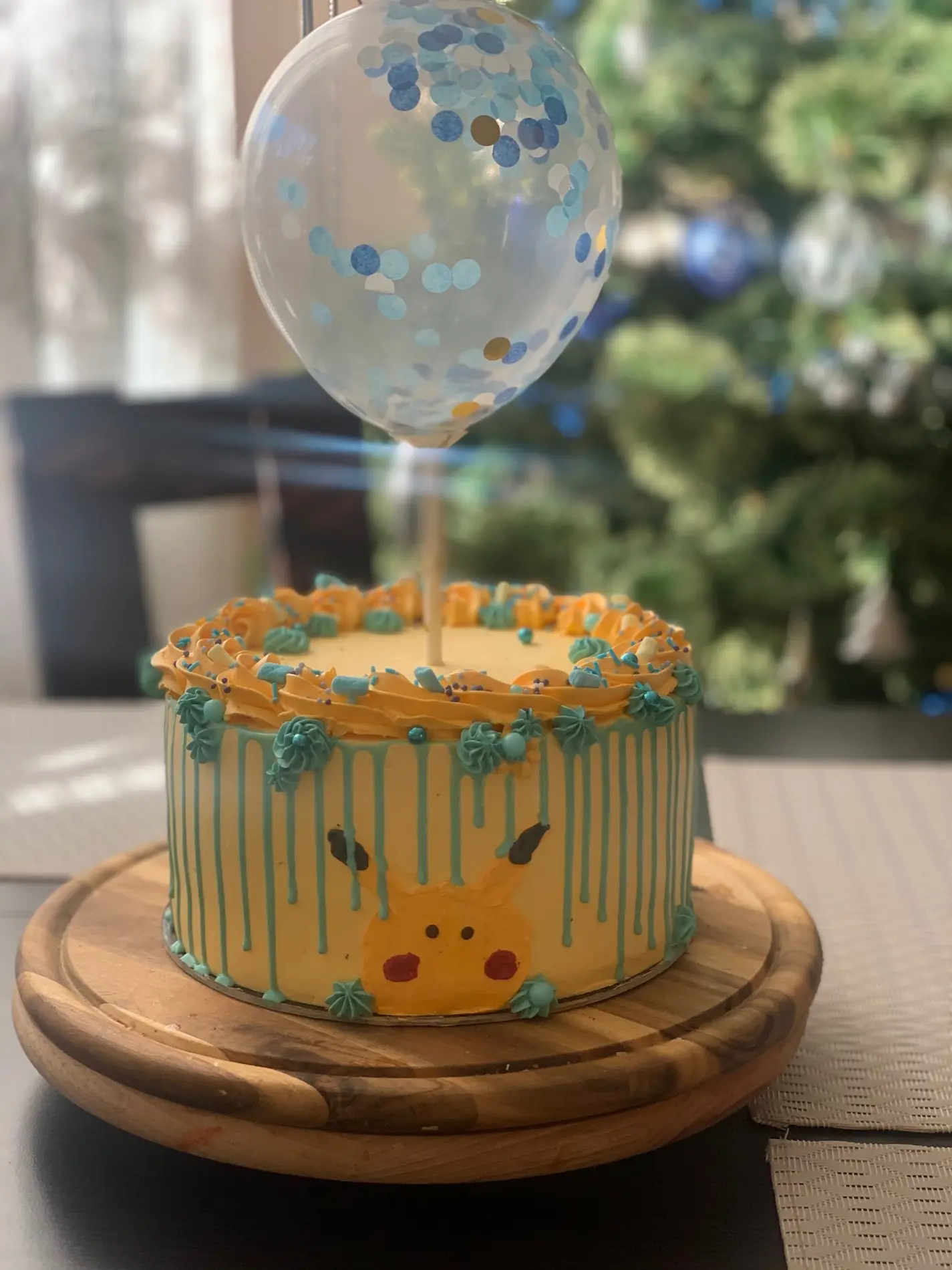 Tort dziecięcy z motywem Pikachu, żółto-niebieską polewą drip i balonem z konfetti