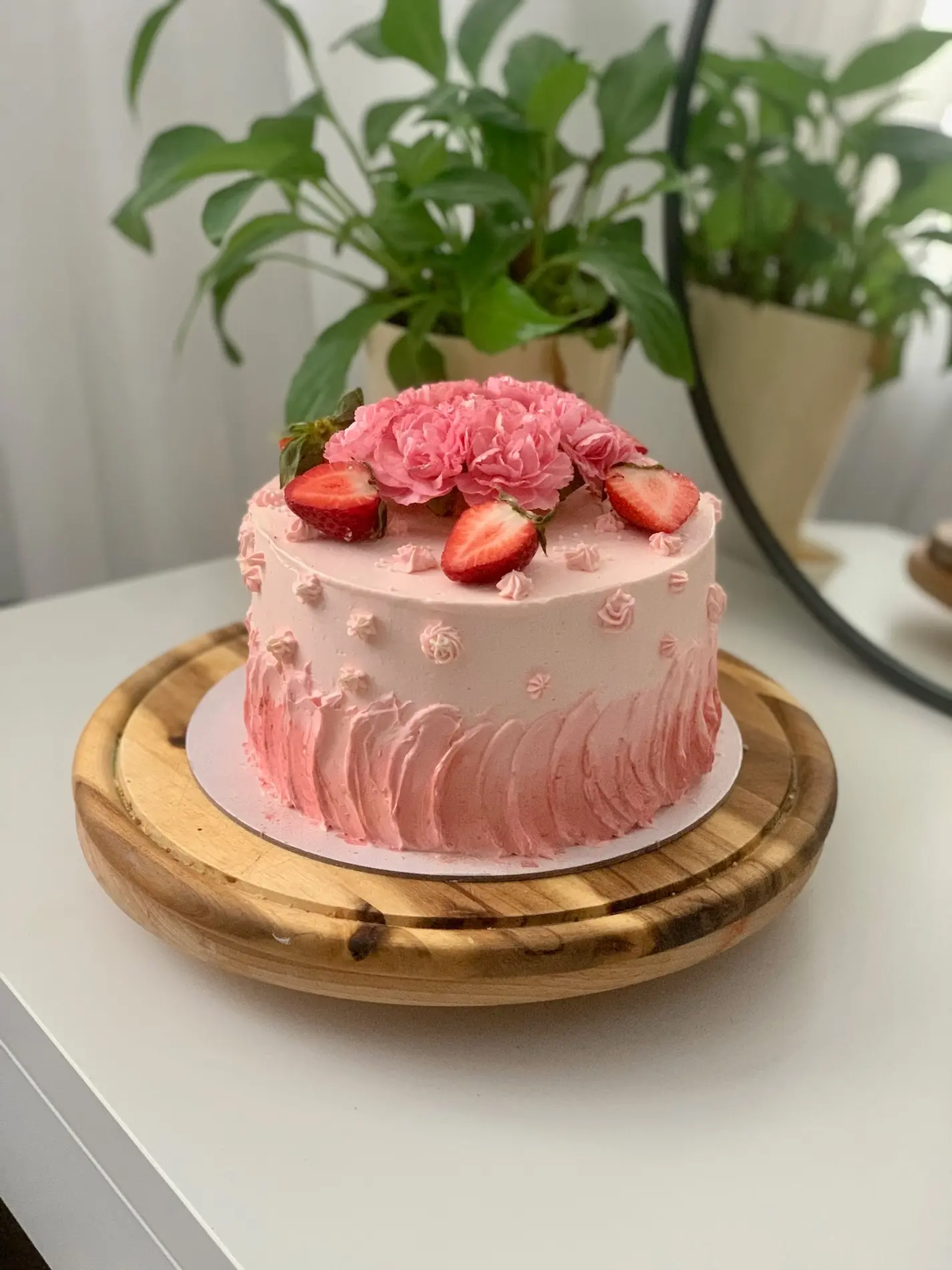 Różowy tort owocowy z gradientem, świeżymi truskawkami i różowymi goździkami