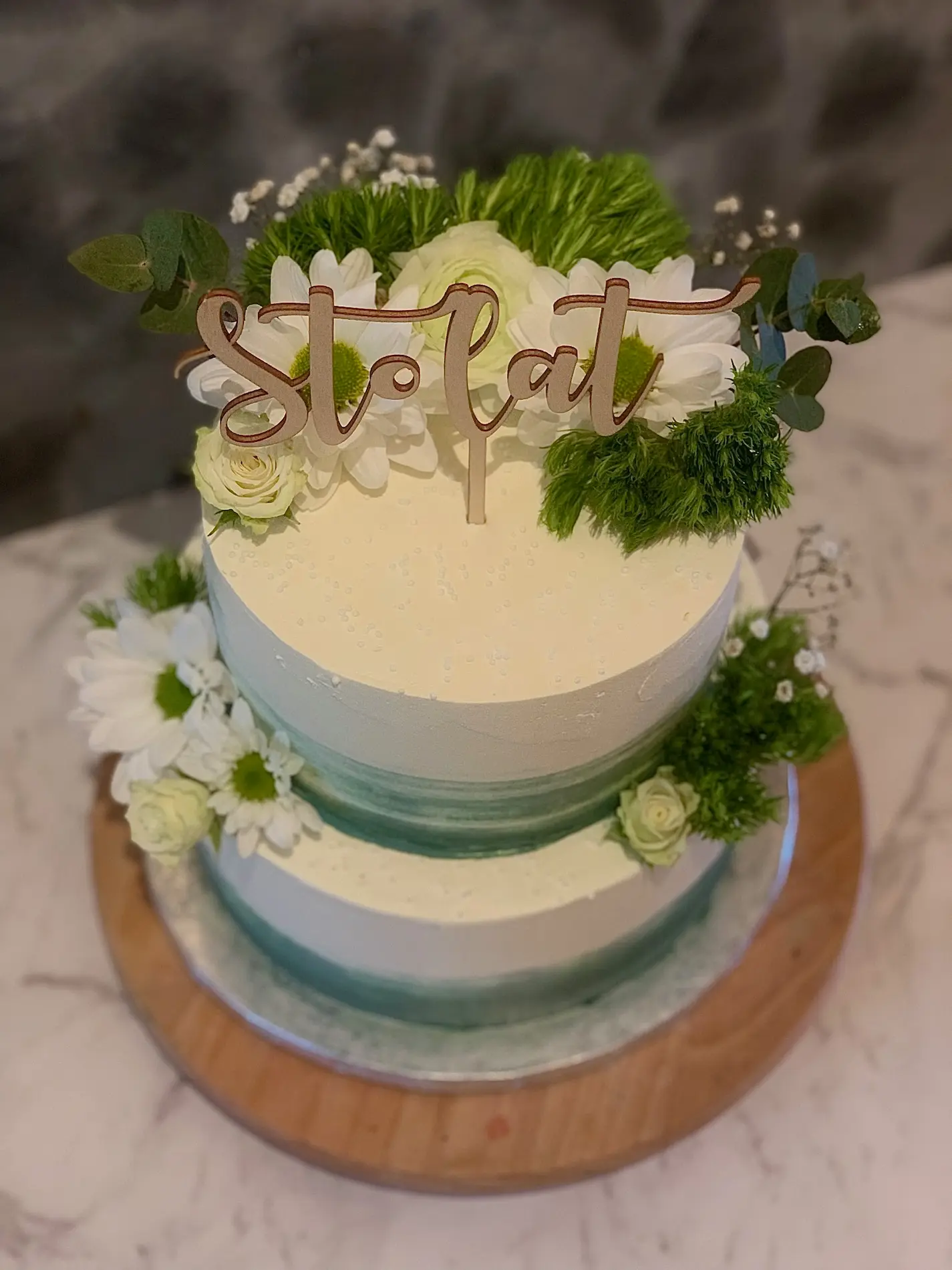 Dwupiętrowy tort jubileuszowy Sto Lat z zielonym gradientem, białymi różami i zielenią dekoracyjną